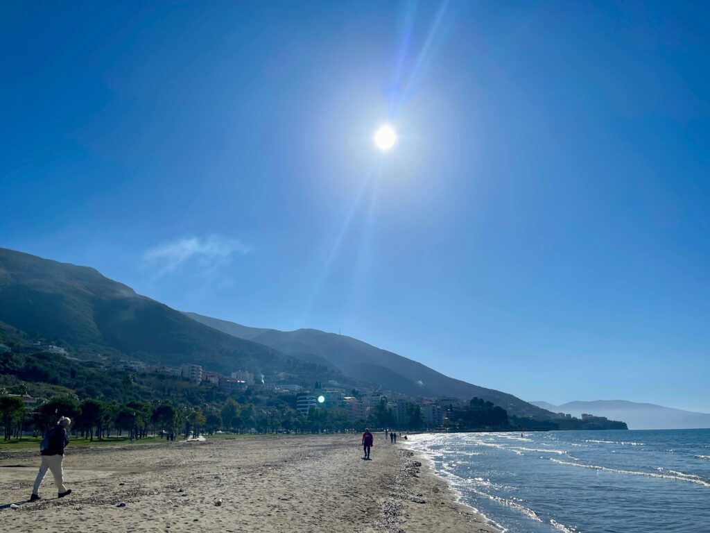 Mensch spaziert Strand vor Bergen