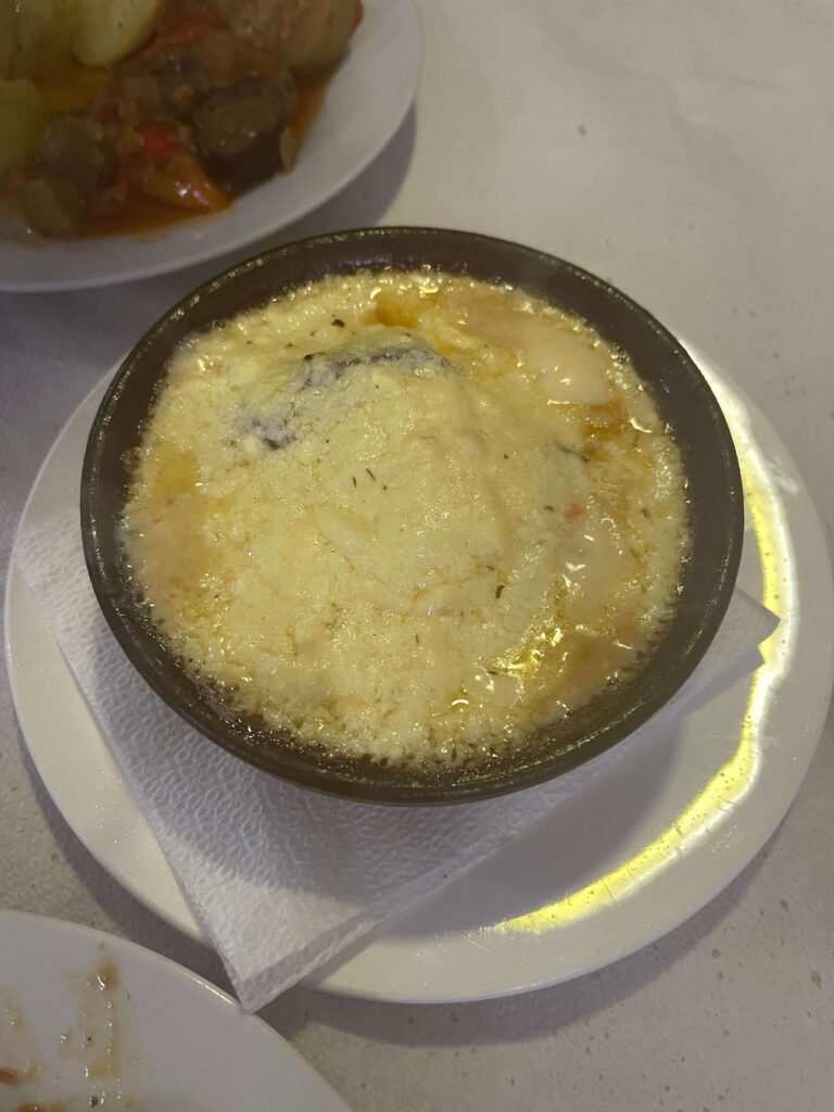 Mit Käse überbackenes Gericht in Tonschale